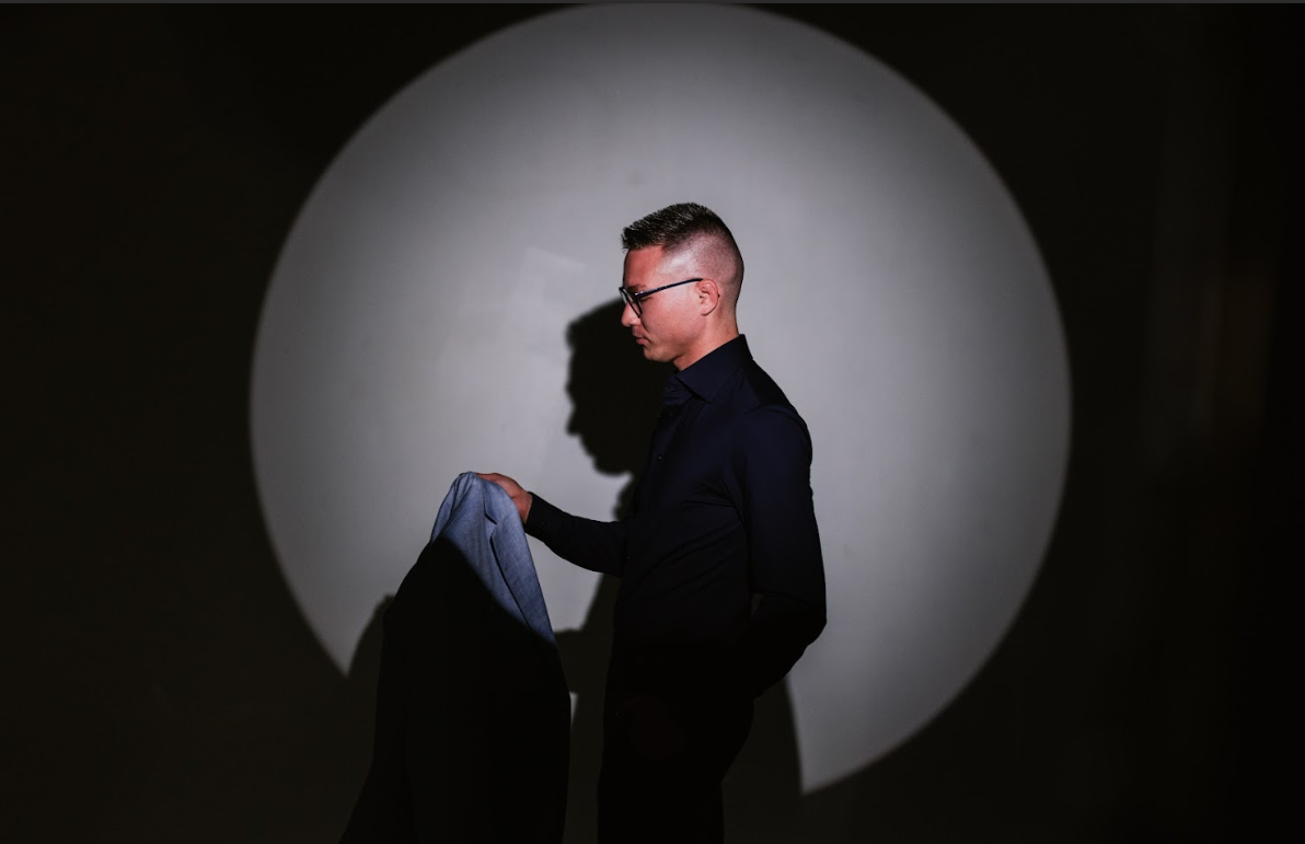 A person smiling while adjusting their outfit in a mirror, representing the psychology of style and how the clothes we choose impact our inner sense of belonging.