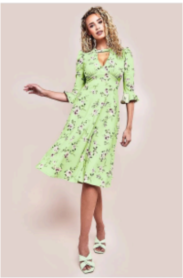 A woman wearing a floral print midi dress standing in a lush green garden setting, perfect for an outdoor wedding.